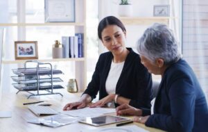 A couple reviews a will and trust documents with a pen at a home office table.
