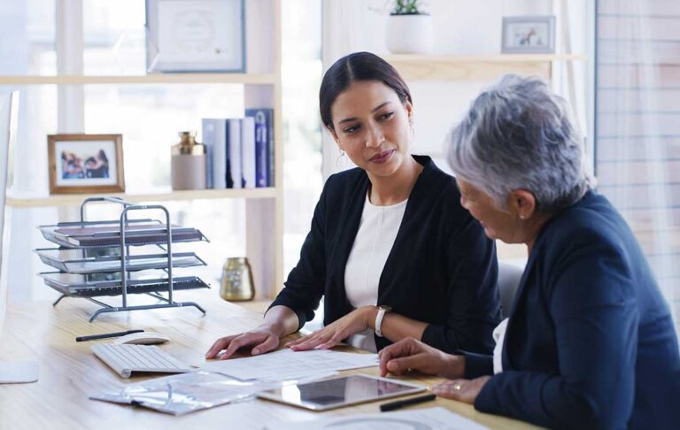 A couple reviews a will and trust documents with a pen at a home office table.